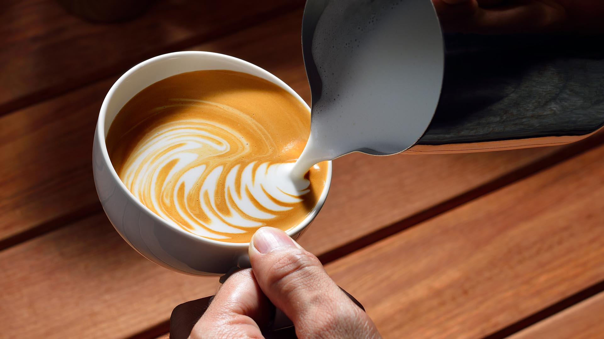 Latte art w filiżance kawy na drewnianym stole.