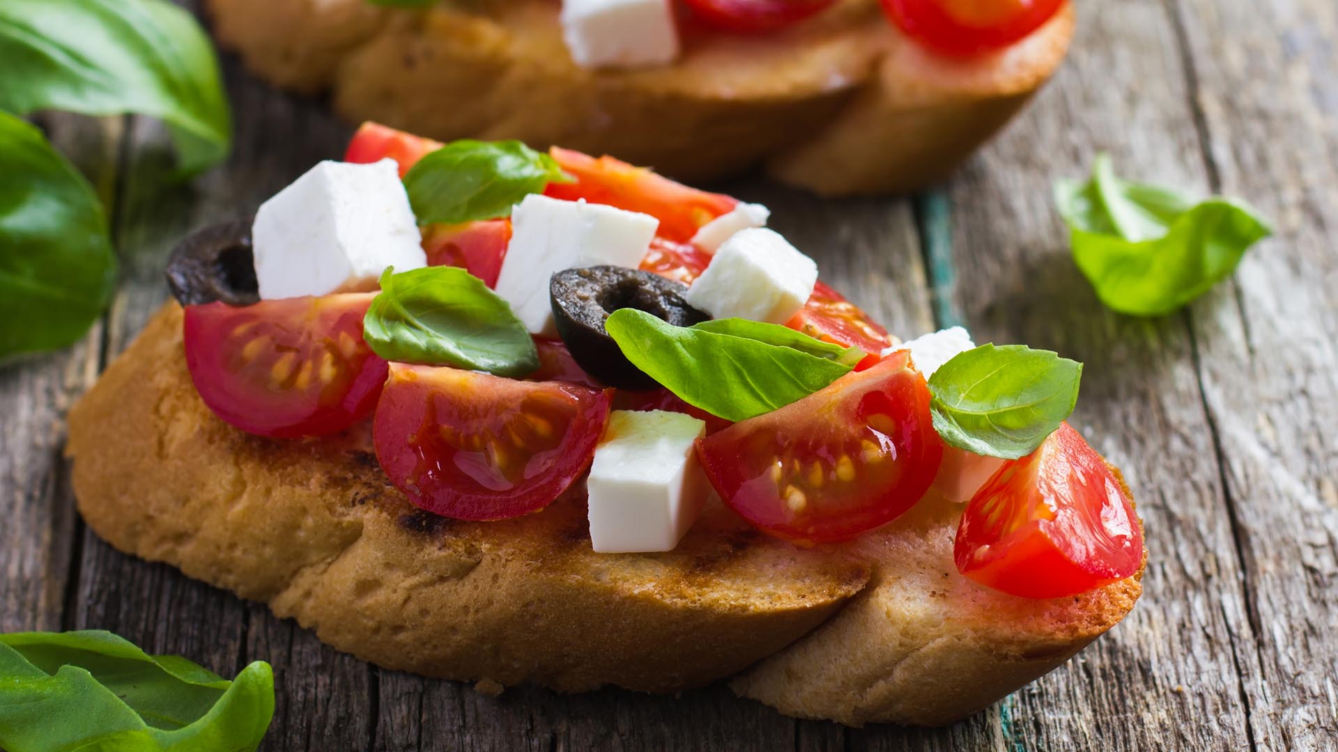 Bruschetta z pomidorami, fetą i bazylią na drewnianym stole