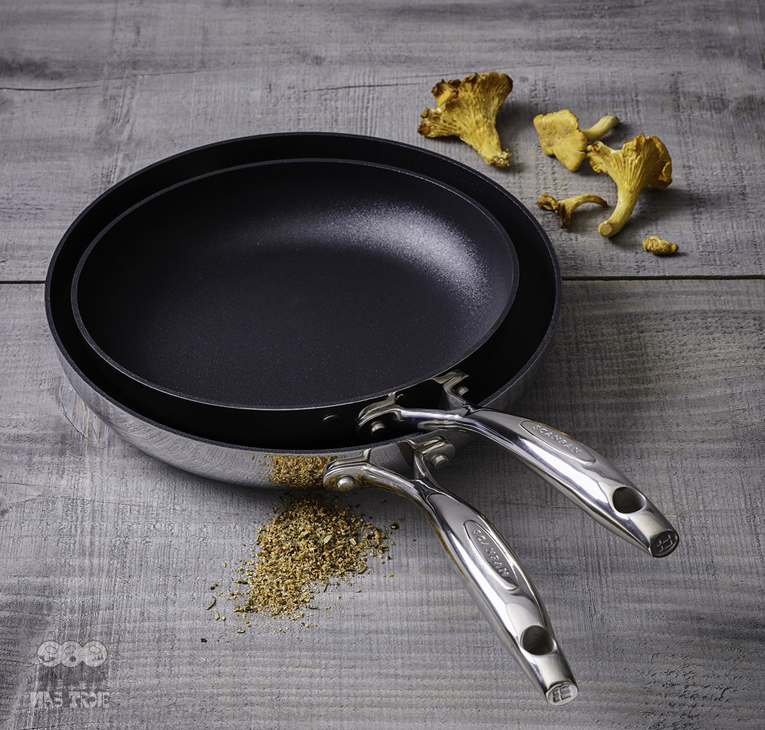 Nieprzywierająca patelnia HaptIQ Scanpan 20 cm z dodatkami kulinarnymi na tle drewnianym. Tytanowo-ceramiczna patelnia Scanpan HaptIQ, Ø 20 cm na drewnianym stole z kurkami i przyprawami.