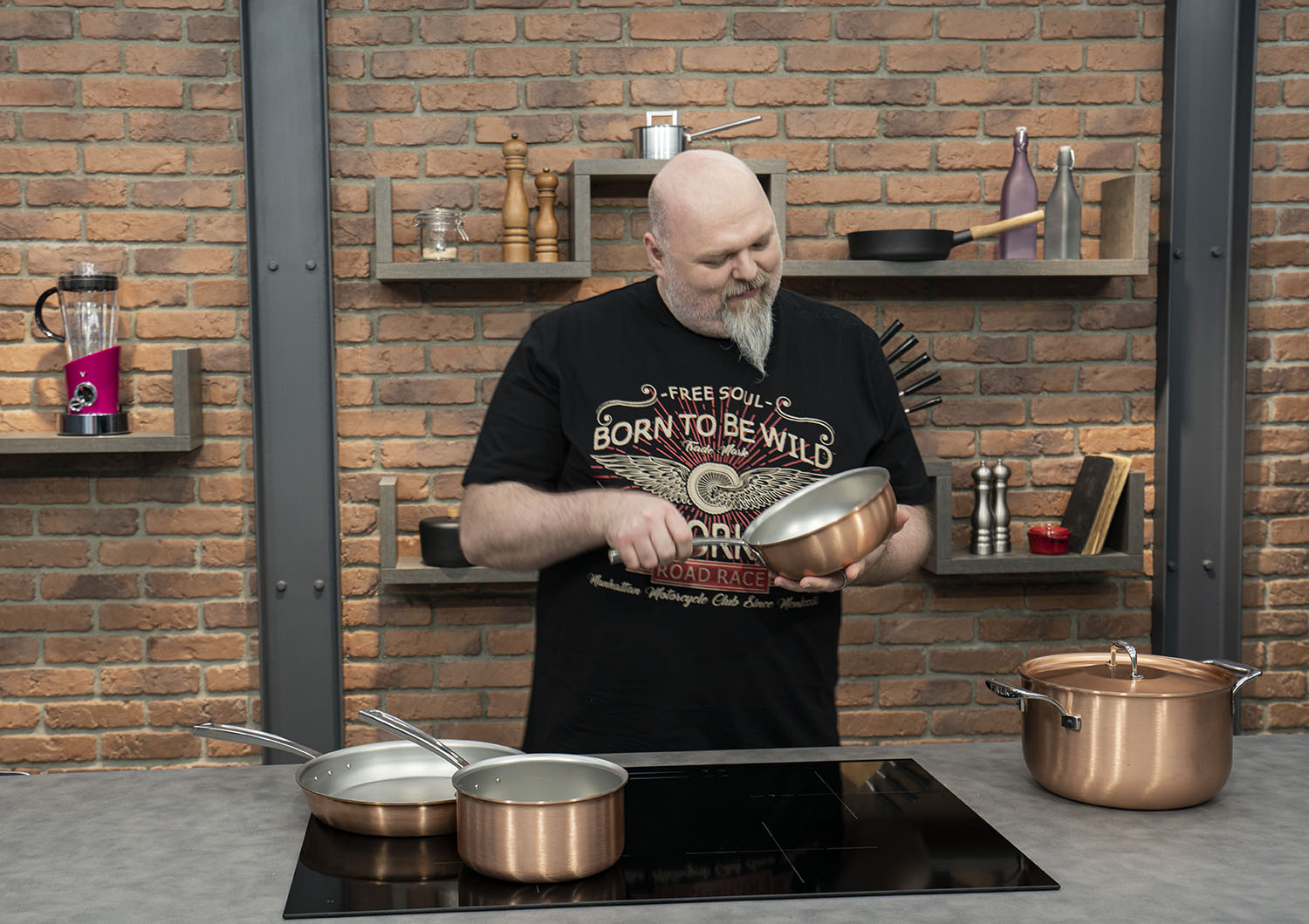 Miedziana patelnia sauté Falk w kuchni na tle ceglanej ściany z półkami.