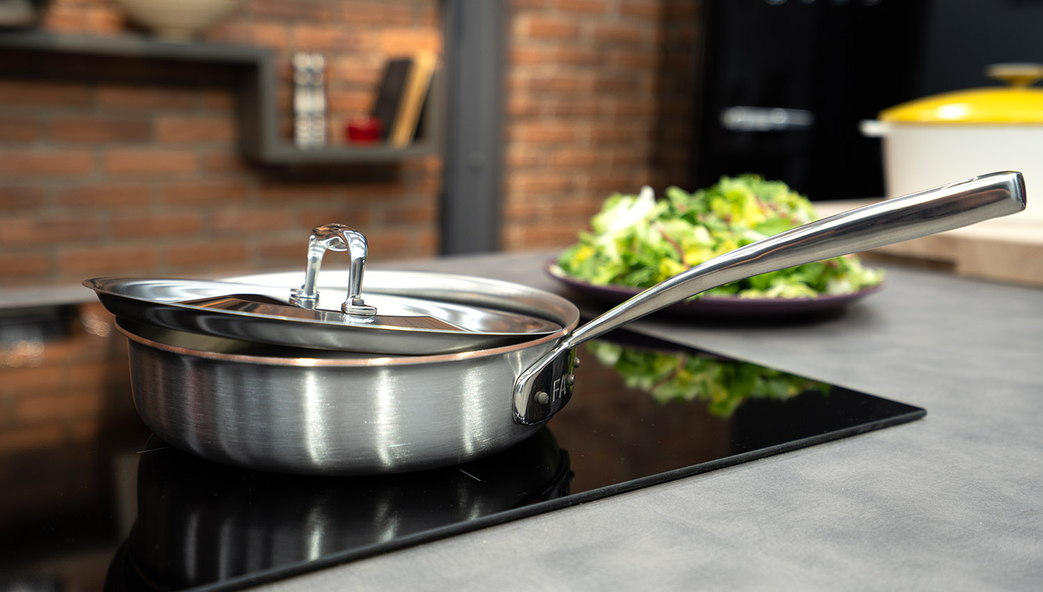 Stalowo-miedziana patelnia sauté Falk z pokrywką na kuchence indukcyjnej w nowoczesnej kuchni.
