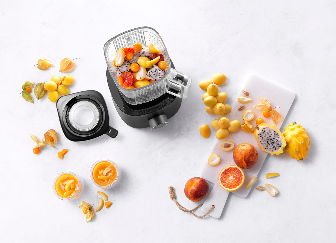 Luksusowy blender Enfinigy Table z owocami egzotycznymi do smoothie. Czarny blender Zwilling z owocami na białym tle, gotowy do przygotowania smoothie.