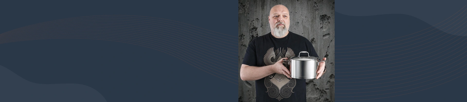 Mężczyzna prezentuje wysoki garnek Demeyere Atlantis 5L ze stali szlachetnej na tle betonowej ściany.