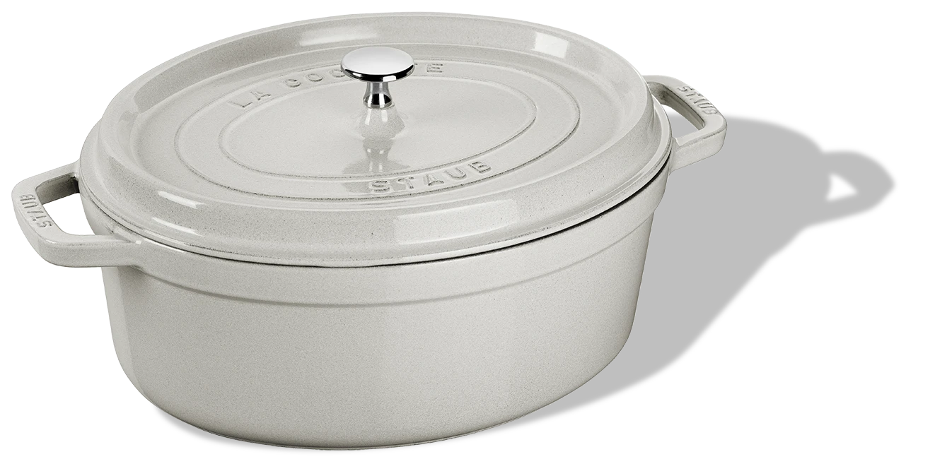 Owalny, żeliwny garnek Staub z białym wykończeniem, pojemność 5,4 l, elegancki design.