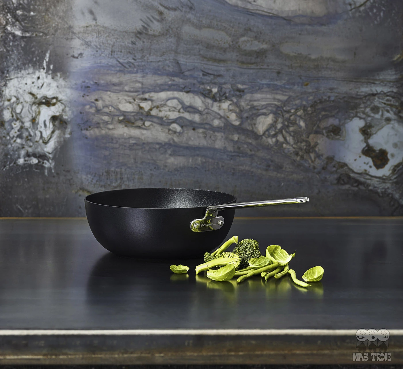 Wok Scanpan z tytanowo-ceramiczną powłoką na tle marmurowej ściany, obok świeże warzywa.