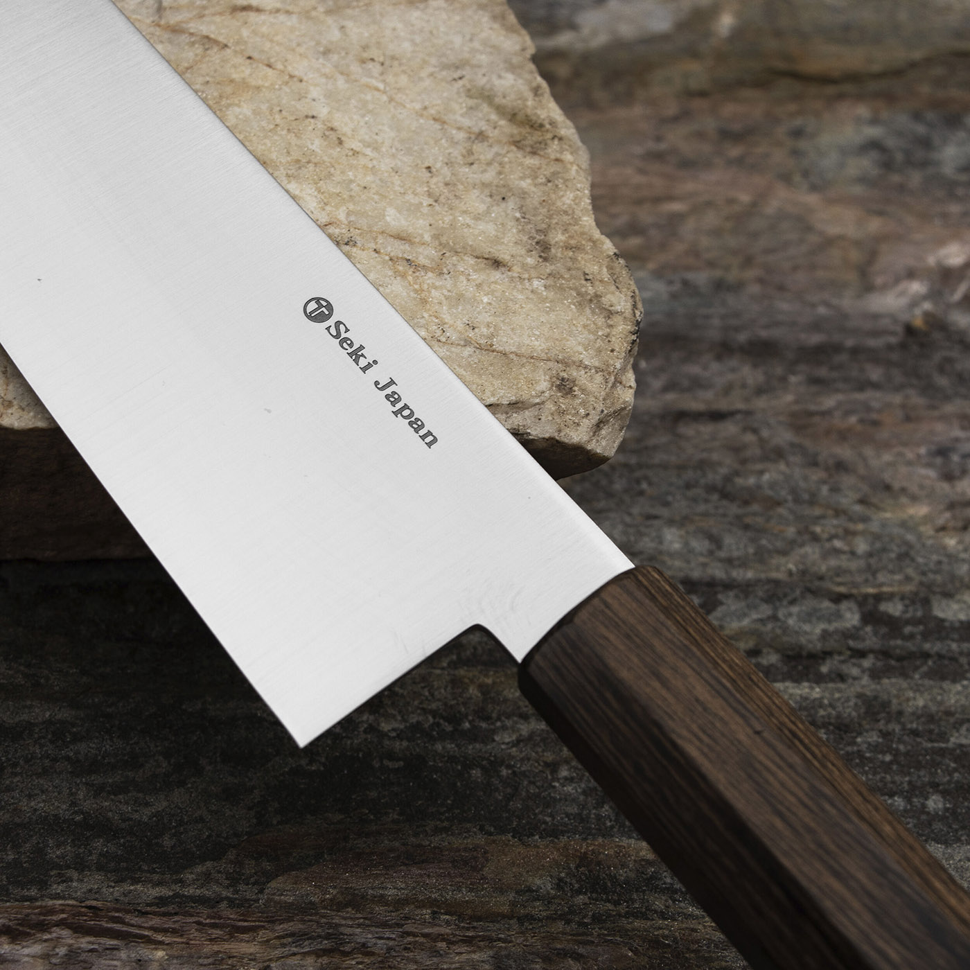 Nóż Santoku VG-10, 18 cm, monoblok, Kanetsune na tle kamienia. Japoński nóż Santoku 18 cm na kamiennej powierzchni, ostrze VG-10, Kanetsune.