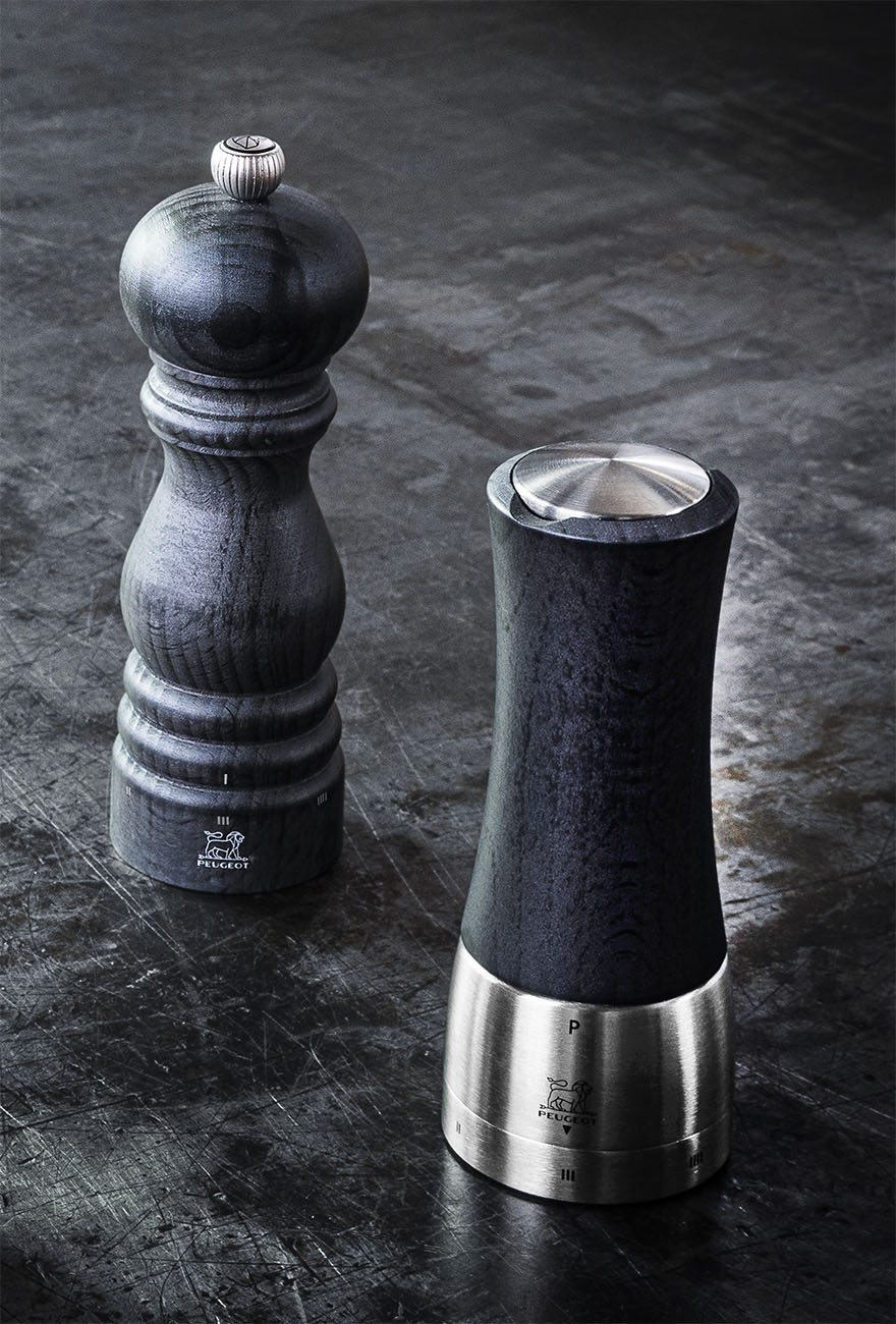 Stylowe młynki do przypraw Peugeot Madras Graphite z mechanizmem U-Select. Francuskie młynki Peugeot Madras Graphite z drewna bukowego na ciemnym tle.