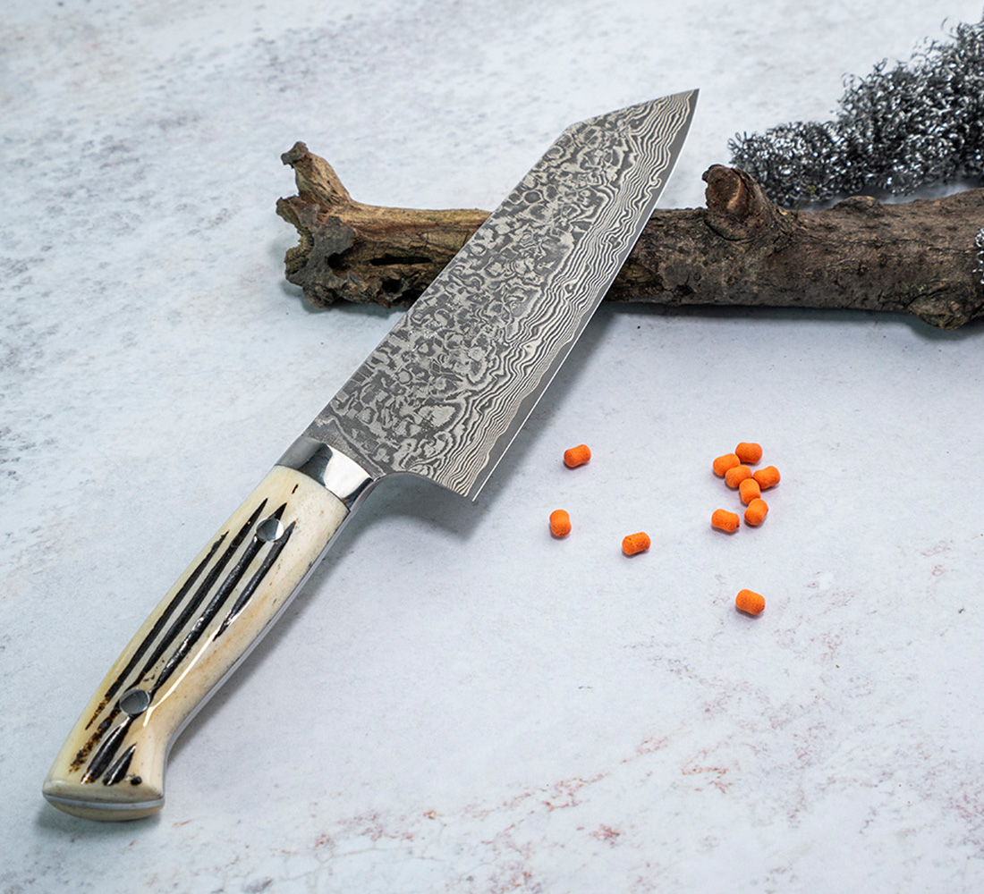 Orientalny nóż Nakiri, stal damasceńska, 17 cm, Takeshi Saji Nóż Nakiri z damasceńskiej stali na tle drewna i pomarańczowych elementów