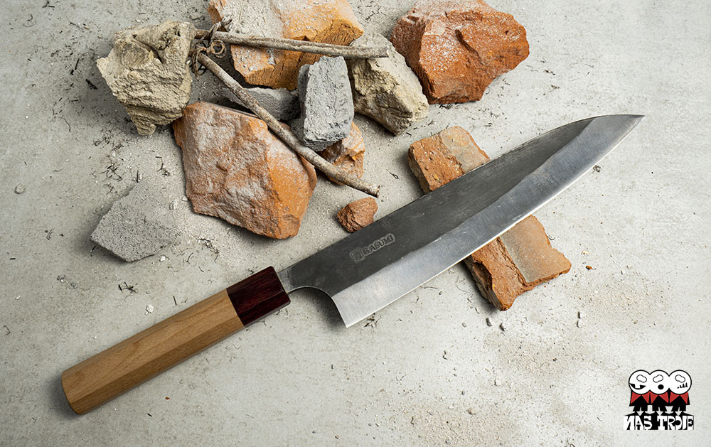 Tradycyjny nóż Santoku Kasumi na tle cegieł i gruzu.
