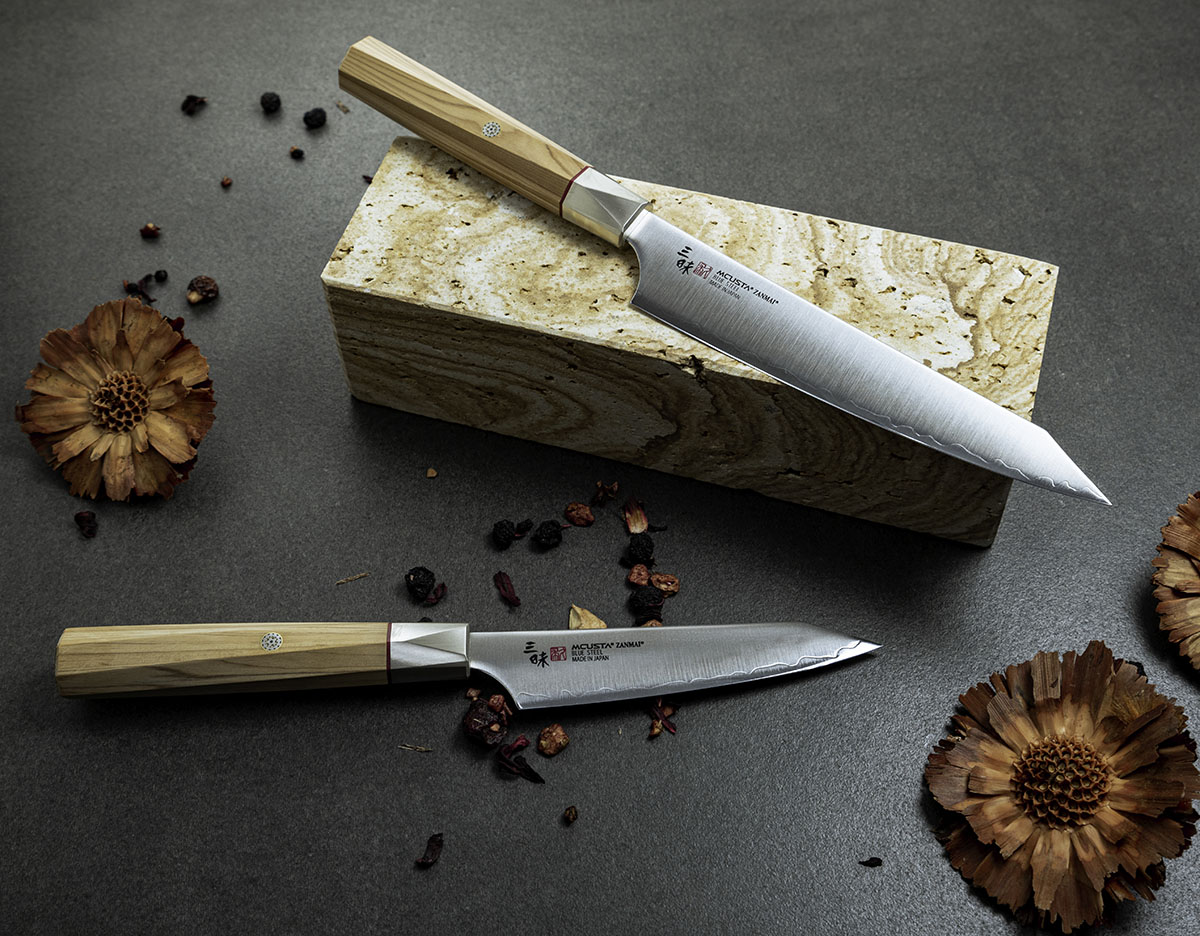 Elegancki nóż kuchenny Shotoh na kamiennej podstawce z dodatkiem suszonych kwiatów. Japoński nóż Shotoh z drewnianą rękojeścią na tle kamienia, ozdobiony suszonymi kwiatami.