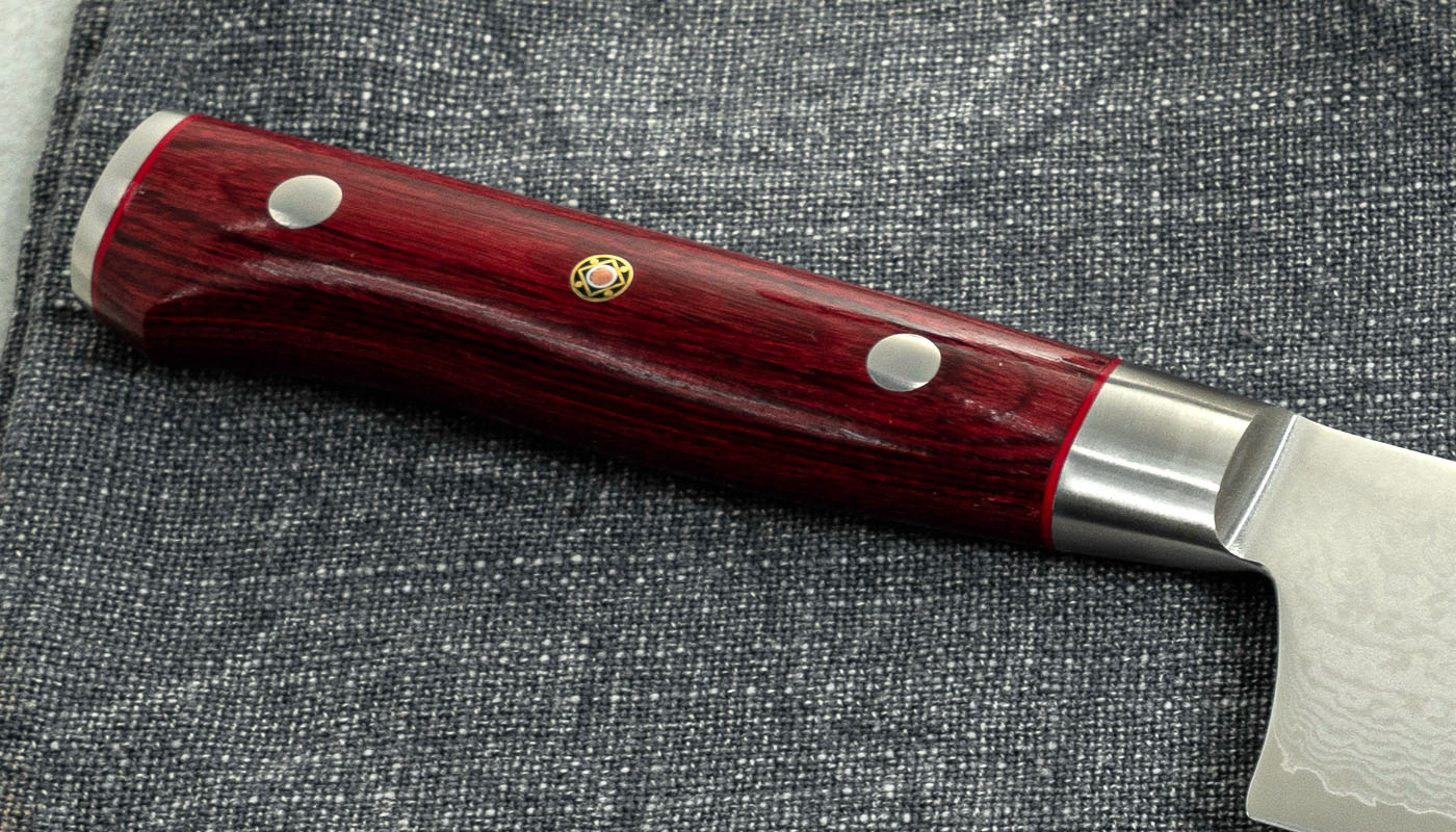 Detal japońskiego noża Nakiri z elegancką rękojeścią Rękojeść japońskiego noża Nakiri Mcusta Zanmai na szarej tkaninie