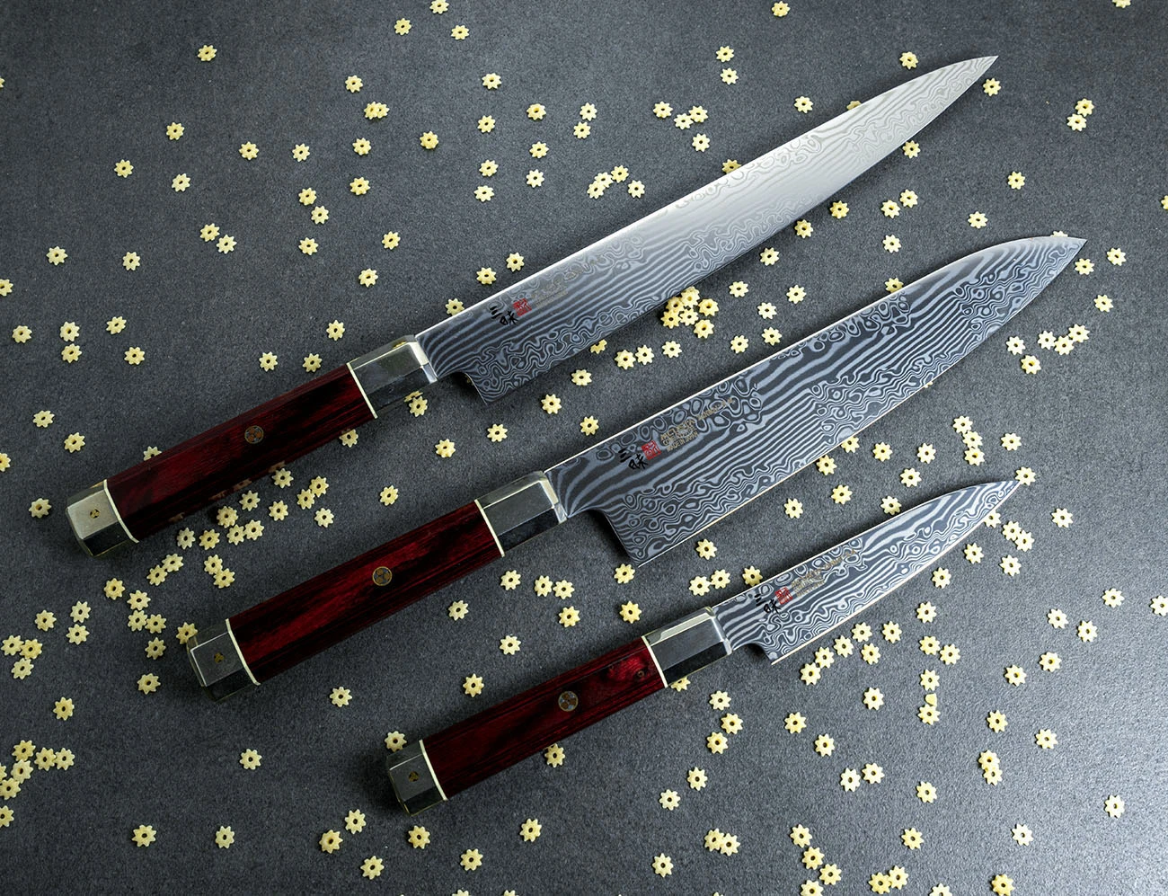 Eleganckie noże Nakiri na tle szarego blatu z dekoracją z makaronu.