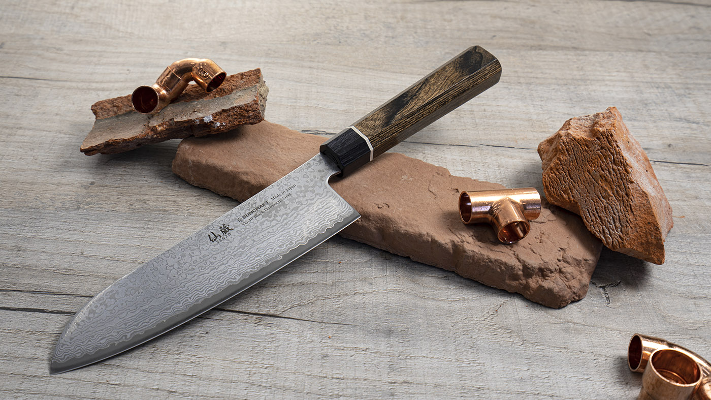 Japoński nóż Santoku Suncraft na tle kamieni i miedzianych elementów