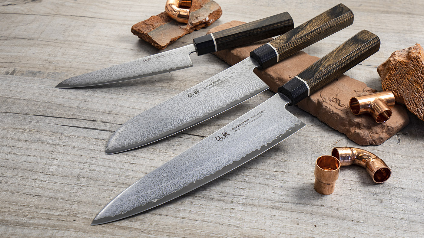 Japoński nóż Bunka Senzo Black z czernioną, 33-warstwową stalą, 16,5 cm, na tle drewnianego stołu.