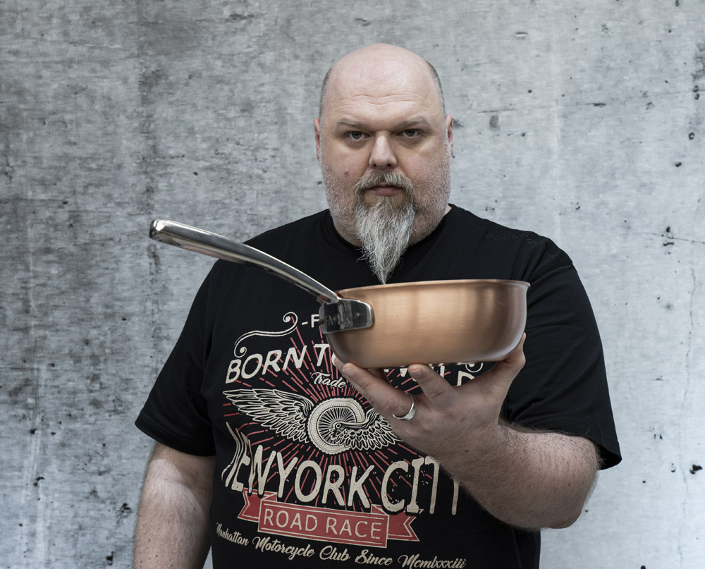 Miedziany wok AvantGarde trzymany przez osobę na tle szarej ściany.