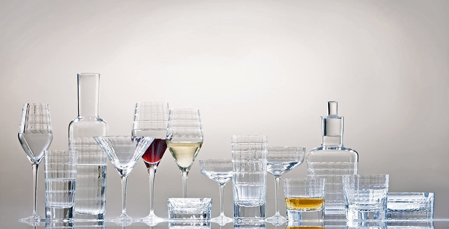 Eleganckie kieliszki i karafki z kryształu Zwiesel GLAS na tle jasnej ściany.