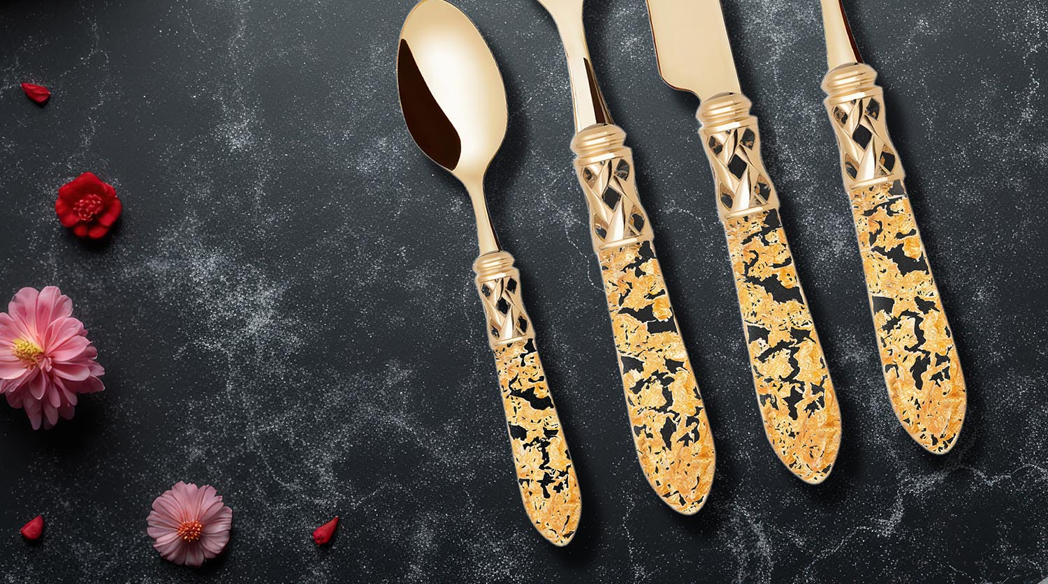 Zestaw sztućców Aladdin Gold Flakes na tle czarnym z dekoracyjnymi kwiatami