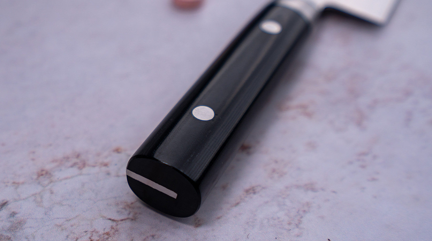 Rękojeść japońskiego noża Santoku o eleganckim designie i nitowanej konstrukcji.