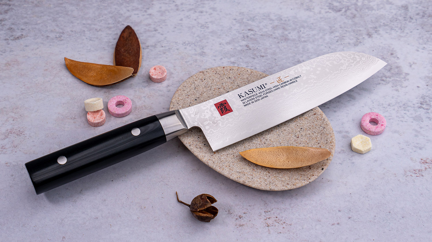 Japoński nóż Santoku Kasumi z damasceńską stalą VG-10, 32 warstwy, na kamiennej powierzchni.