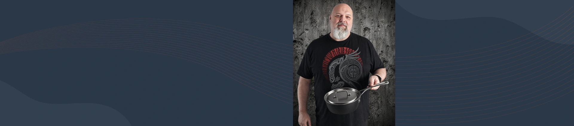 Mężczyzna trzyma stalowo-ceramiczną patelnię sauté Demeyere Black 5 na tle betonowej ściany