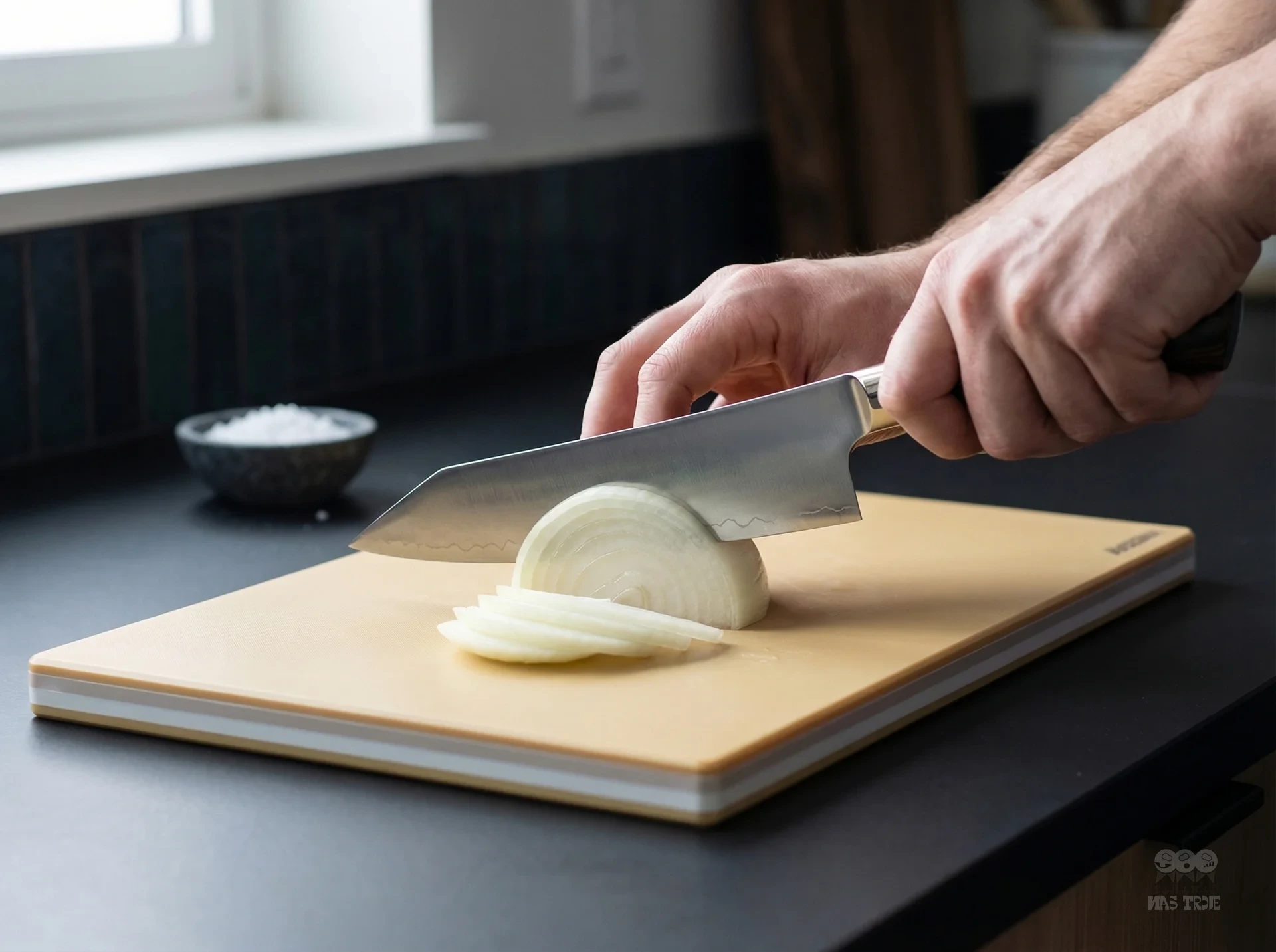 Precyzyjne krojenie cebuli nożem Santoku SG2 na desce kuchennej w nowoczesnej kuchni