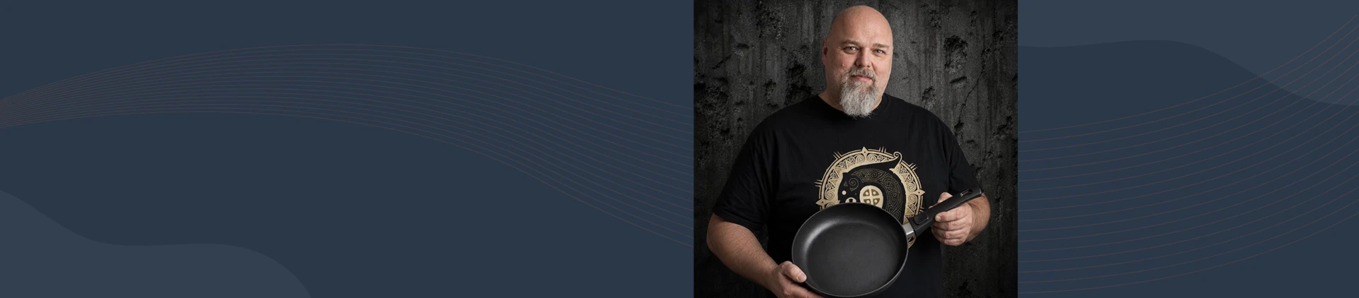 Mężczyzna prezentuje tytanowo-ceramiczną patelnię Scanpan z odpinanym uchwytem na tle ciemnej ściany