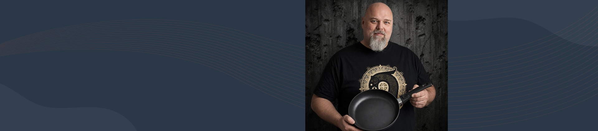 Mężczyzna prezentuje tytanowo-ceramiczną patelnię Scanpan z odpinanym uchwytem na tle ciemnej ściany