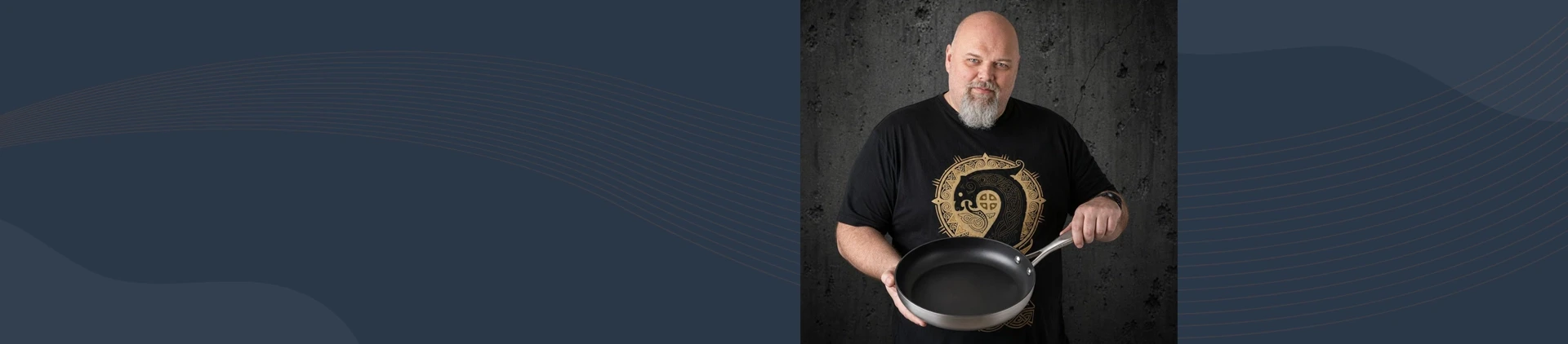 Mężczyzna prezentuje tytanowo-ceramiczną patelnię Scanpan o średnicy 26 cm na tle ciemnej ściany.