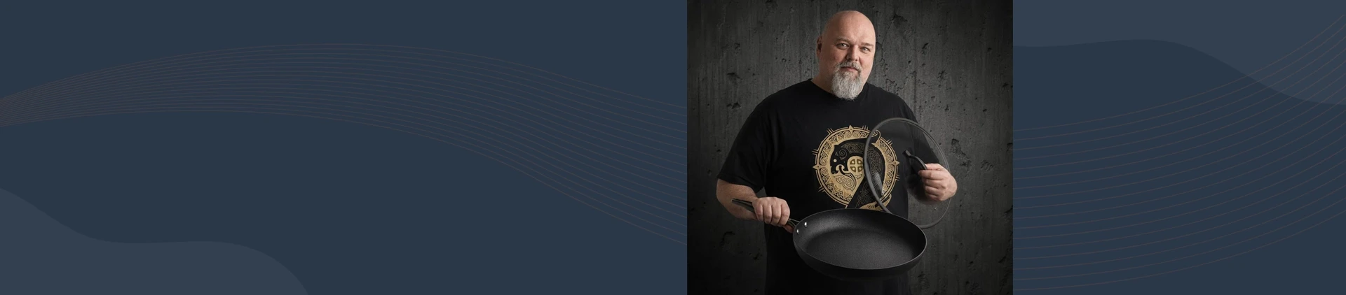 Mężczyzna trzyma dużą patelnię tytanowo-ceramiczną Scanpan z pokrywką na tle ciemnej ściany