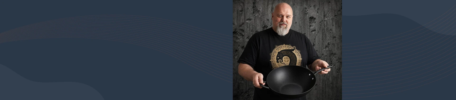 Mężczyzna prezentuje tytanowo-ceramiczny wok Scanpan Pro SB+ o średnicy 32 cm na tle szarej ściany
