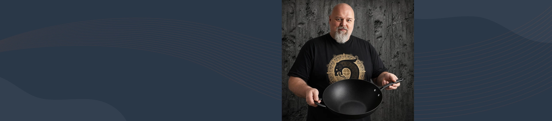 Mężczyzna prezentuje tytanowo-ceramiczny wok Scanpan Pro SB+ o średnicy 32 cm na tle szarej ściany