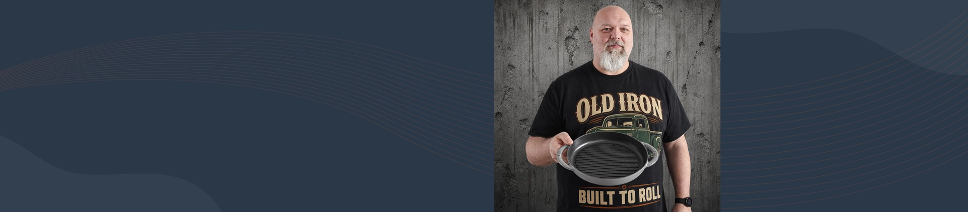 Mężczyzna prezentuje żeliwną patelnię grillową Staub Pure Grill Graphite Grey na tle betonowej ściany