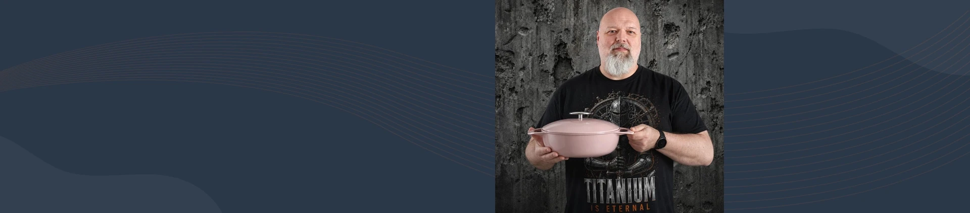 Mężczyzna trzyma różowy, żeliwny garnek Sakura o pojemności 2,6 l marki Unilloy na tle szarej ściany