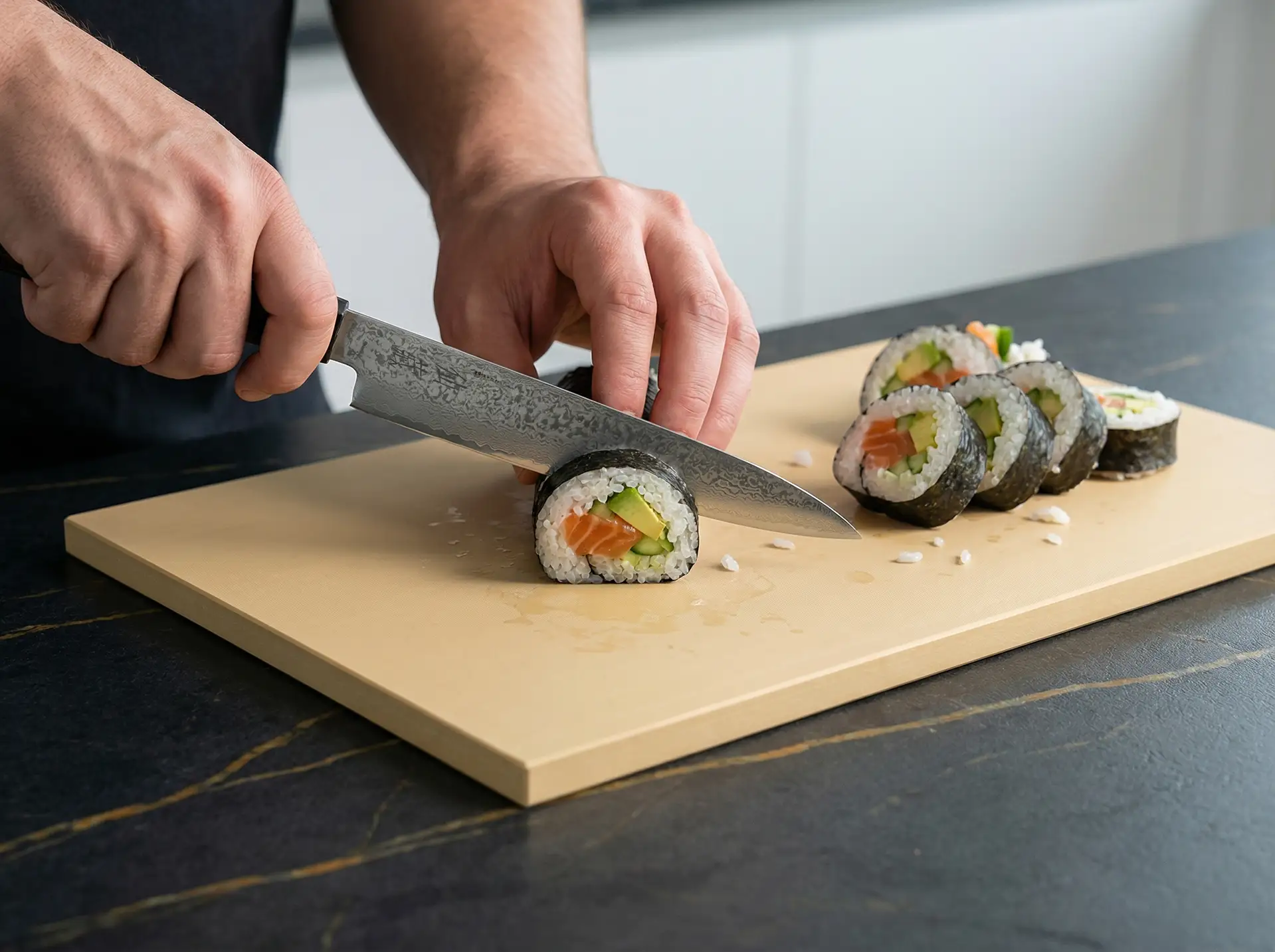 Krojenie sushi nożem japońskim Senzo Black na desce w nowoczesnej kuchni, widok z bliska.