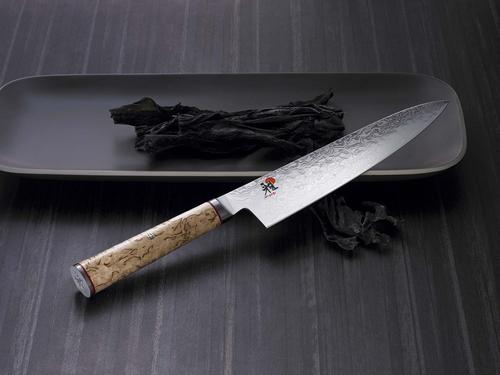 Nóż Miyabi Gyuto 5000 MCD na ciemnym tle z eleganckim wzorem damasceńskim.