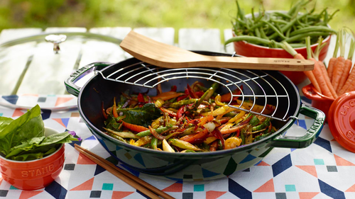 Staub wok żeliwny czarny z warzywami na stole w ogrodzie