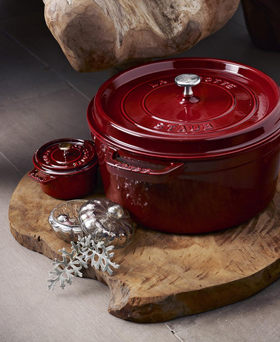 Żeliwny garnek Staub Grenade Red na drewnianej desce, elegancki design