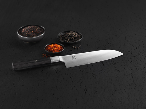 Japoński nóż Santoku Miyabi 4000 FC na ciemnym tle z przyprawami.