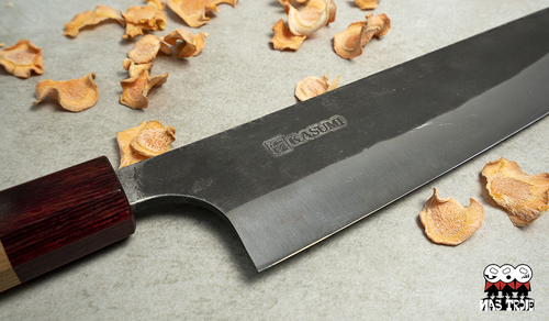 Tradycyjny nóż Gyuto Kasumi Black Hammer, ręcznie kuty, 21 cm, na tle chipsów.