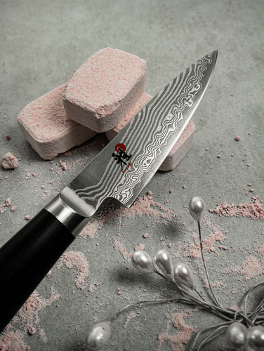 Damasceński nóż kuchenny Miyabi 5000 FCD Gyutoh na tle kamieni