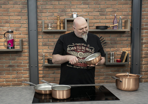 Wok miedziany Falk Signature do risotto, dwa uchwyty, 3 litry na tle ceglanej ściany.