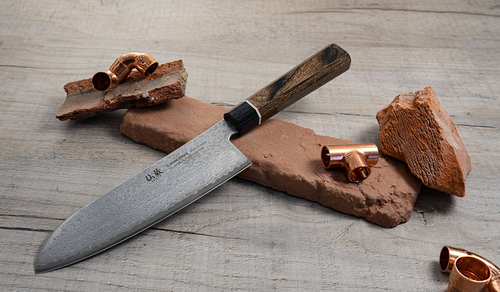 Senzo Black Suncraft - japoński nóż Santoku na tle cegieł i miedzi