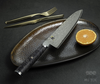 Nóż kucharski Miyabi Gyuto 5000 MCD Black 67 na eleganckim tle z pomarańczą.
