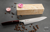 Japoński nóż Santoku Mcusta Zanmai Revolution SPG2 na tle kawowych ziaren.