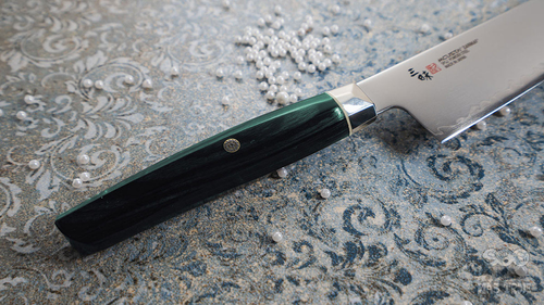 Nóż Kiritsuke Mcusta Zanmai Revolution SPG2, 23 cm, na ozdobnym tle.