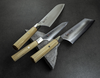 Nóż Santoku Mcusta Zanmai Beyond, stal Aogami Super, 18 cm, na kamiennym tle.