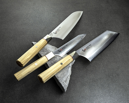Japoński nóż Bunka Mcusta Zanmai Beyond, stal Aogami Super, 18 cm, na kamiennym tle.