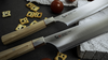 Mcusta Zanmai Beyond - japoński nóż Gyuto, stal Aogami Super, 24 cm, na tle przekąsek.