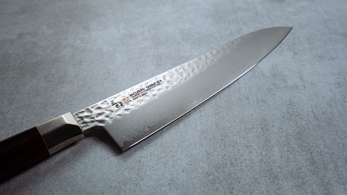 Nóż damasceński Mcusta Zanmai Supreme Hammered na blacie kuchennym