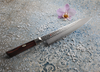 Krótki nóż kucharza Mcusta Zanmai Gyuto z serii Supreme Hammered na ozdobnym tle.